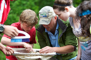 Teacher students looking macroinvertebrate Teacher outdoors with students
